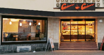 Eingangsbereich hell erleuchtet mit Auslage und Blick ins Cafe