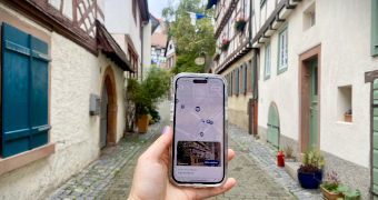 Eine Hand mit Handy und Zeigmal App im Gerberbachviertel