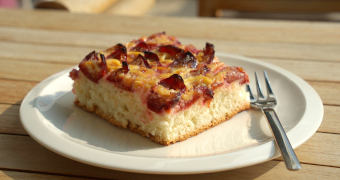 Ein Stück Zwetschgenkuchen auf einem weißen Teller mit Gabel