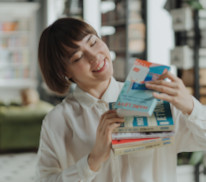 Eine Frau hat mehrere Bücher in der Hand und schaut sich einen Einband an.