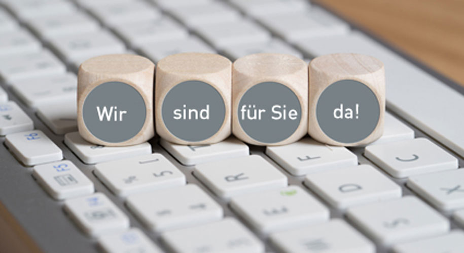 Vier Würfel auf einer Tastatur mit dem Satz "Wir sind für Sie da!"