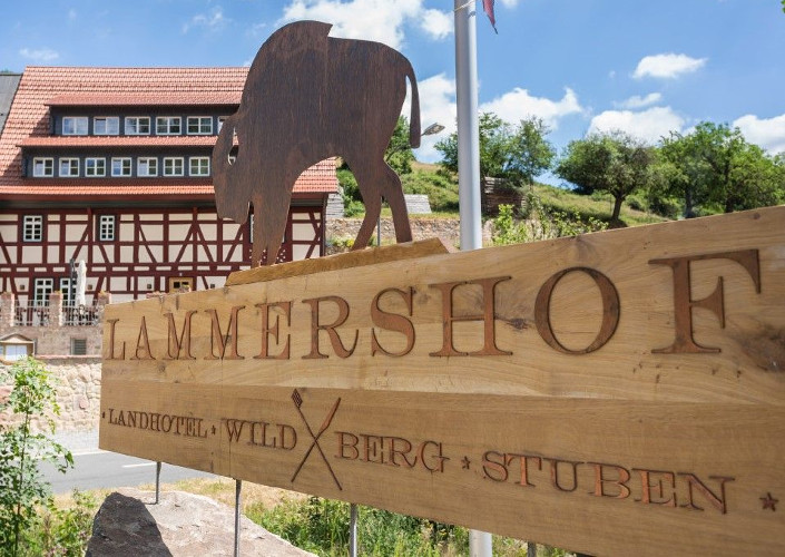 Hölzernes Schild mit Bison und Schriftzug Lammershof vor dem Fachwerkgebäude