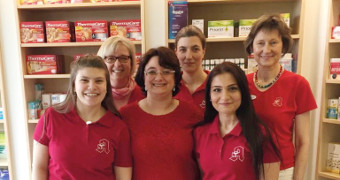Das Team der Apotheke trägt rote T-Shirts und lächelt in die Kamera