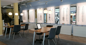 Tische mit Sitzmöglichkeit für Beratung, Brillengestelle an der Wand mit Spiegeln
