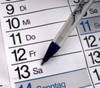 Ein Kalenderblatt mit einem Stift der auf ein Datum zeigt.